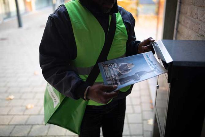 promo courier puts municipal information leaflets in the letterbox